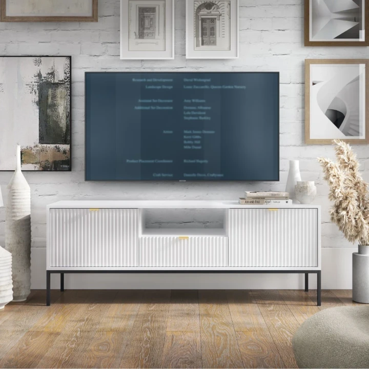 Szafka RTV Nuo biała z ryflowanymi drzwiczkami i szufladą z czarnymi nogami